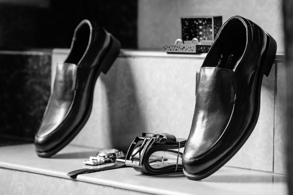 Stylish black leather formal shoes paired with accessories in a black and white setting.